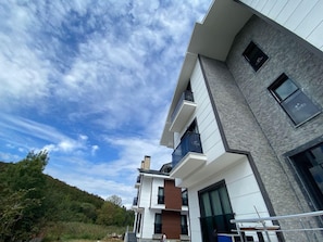 A modern multi-story building with balconies, large windows, and a view of a hill. - Agva Capella Hideaway - Adults Only (Şile)