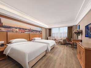 A hotel room with two beds, a desk, a chair, and a view of a cityscape. - Vienna International Hotel Guang'anmen (Beijing)