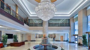 A spacious lobby with a central fountain, a grand chandelier, and multiple levels with balconies. - Vienna International Hotel Guang'anmen (Beijing)