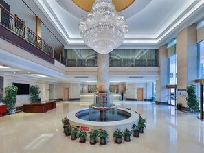 A spacious lobby with a central fountain, a grand chandelier, and multiple levels with balconies. - Vienna International Hotel Guang'anmen (Beijing)