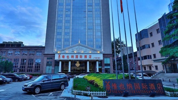 A tall hotel building with a classical facade and a signboard in front. - Vienna International Hotel Guang'anmen (Beijing)