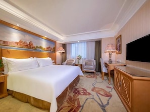 A hotel room with a large bed, a desk, a chair, a television, and a painting on the wall. - Vienna International Hotel Guang'anmen (Beijing)