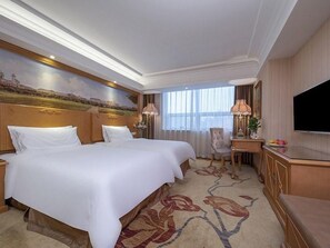 Une chambre d’hôtel avec un grand lit, un bureau, une chaise et un téléviseur.