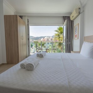 A hotel room with a bed, a wardrobe, a balcony with a view of buildings and palm trees. - Badoka Boutique Hotel (Marmaris)