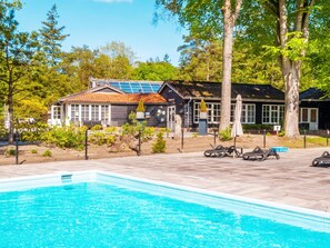 A swimming pool area with a house in the background, surrounded by trees. - Cabin in the Drenthe Countryside (Ruinen)