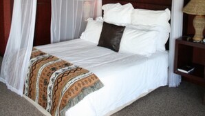 Una cama con dosel, una lámpara de noche y una manta estampada.