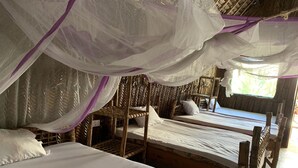 A room with two wooden beds, white bedding, and a mosquito net overhead. - Jambo Beach Bungalows - Hostel (Paje)
