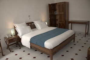 A bedroom with a bed, bedside tables, a wardrobe, and a small table. - Hôtel Villa Les Orchidées (Cotonou)