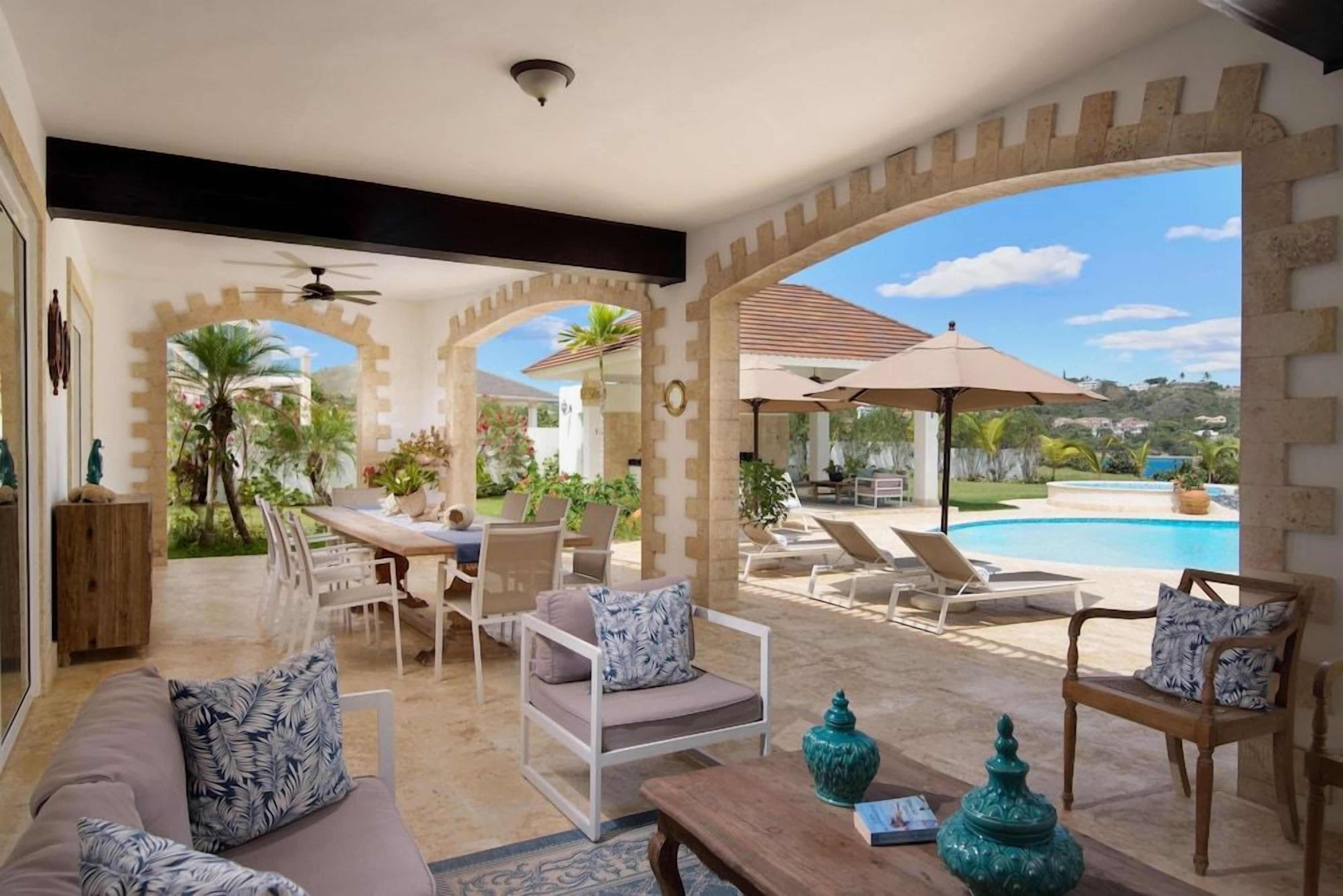 An outdoor patio area with a pool, seating arrangements, and a view of the surrounding landscape.