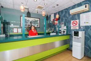 A reception desk with a woman behind it, a water dispenser, and a no-smoking sign. - OYO 539 Dowifi Hotel (Sungai Petani)