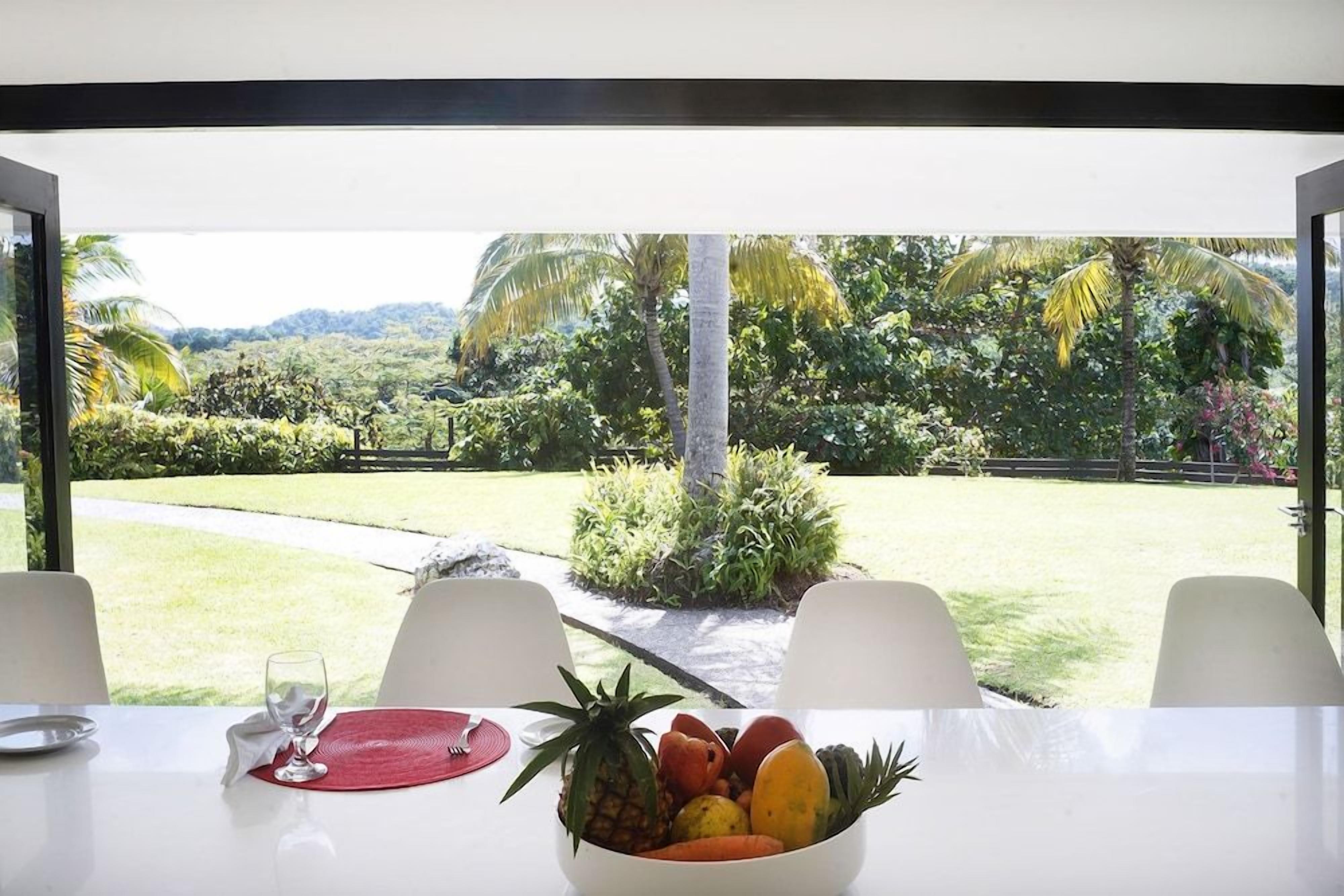 A dining table with a fruit bowl, two chairs, and a glass of water.