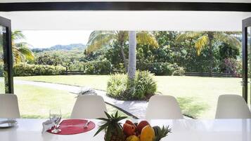 A dining table with a fruit bowl, two chairs, and a glass of water.