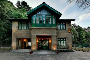 Un edificio de dos plantas con un estilo arquitectónico tradicional, que destaca una entrada con puerta verde y ventanas.
