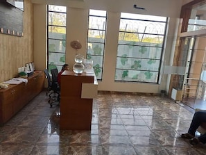 Una habitación con un escritorio de madera, una silla, un acuario y ventanas grandes con vistas.