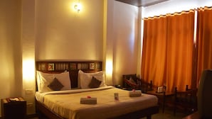 A hotel room with a bed, bedside tables, a chair, and a curtain.