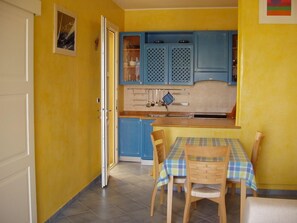 Una cocina con armarios azules, una mesa de comedor con mantel a cuadros y sillas.