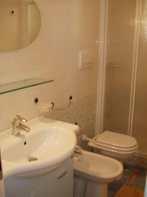 Un baño con lavamanos, espejo, inodoro y bidé.