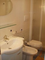 Un baño con lavamanos, espejo, inodoro y bidé.