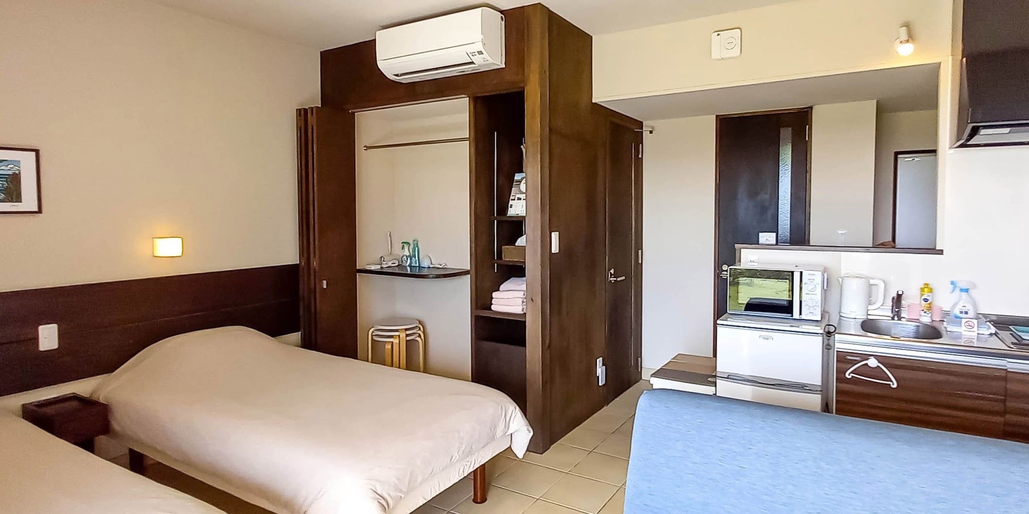 A hotel room with a bed, a desk with a microwave, and a small kitchenette.