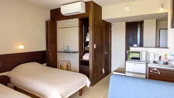 A hotel room with a bed, a desk with a microwave, and a small kitchenette.