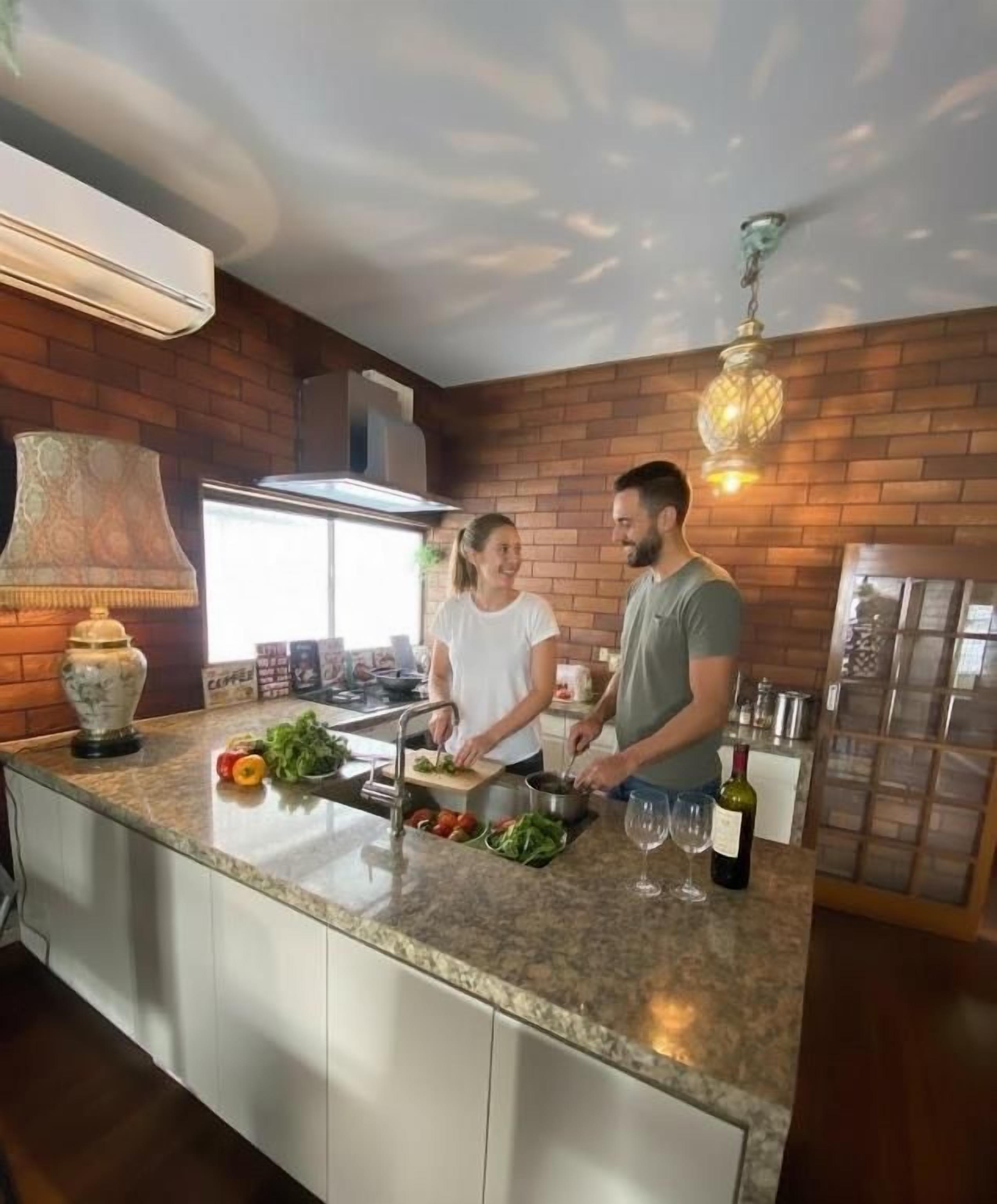 A kitchen with a granite countertop, a built-in oven, and a hanging light fixture.