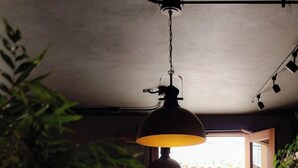 Um espaço interior com área de refeições, incluindo uma mesa e cadeiras, luminária pendente e vista para o exterior através de uma porta aberta.