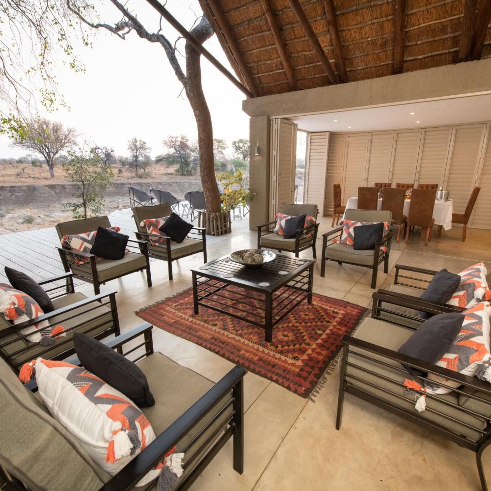 An outdoor seating area with sofas and chairs, a coffee table, and a view of the landscape.