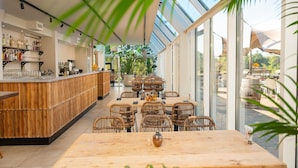 A restaurant with a bar area, wicker furniture, and large windows. - Family Lodge With Garden Retreat in Wilsum (Wilsum)