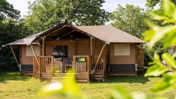 A single-story, A-frame-style cabin with a porch, a bed, and a small table.