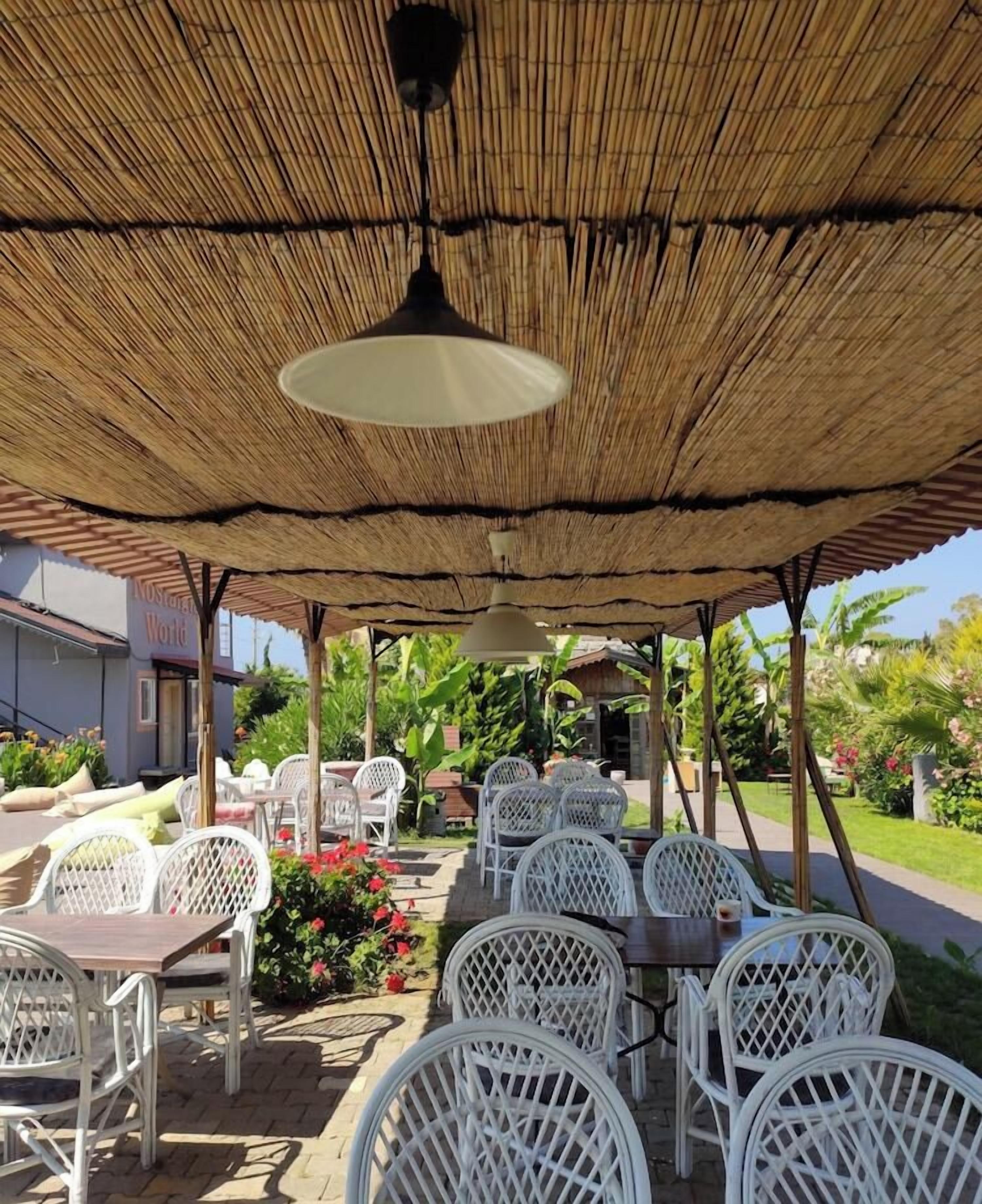 An outdoor patio with white wicker furniture, a thatched roof, and a sign reading 'Restroom World'.