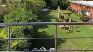 Vista d'un hotel amb un jardí ben cuidat, zona d'estar a l'aire lliure i un edifici amb nombrosos balcons.