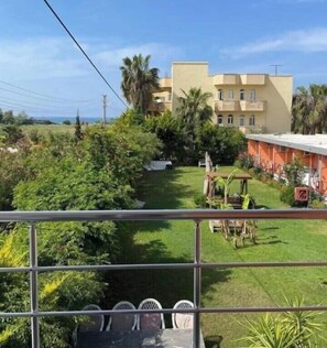 A view of a hotel with a well-maintained lawn, outdoor seating area, and a building with multiple balconies. - Nostalgia Camping Pension (Manavgat)