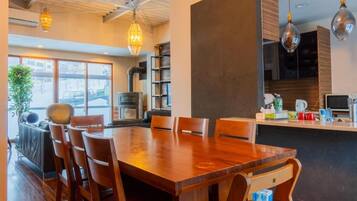 A modern dining area with a wooden table and chairs, a kitchen area with a stove, and pendant lighting.