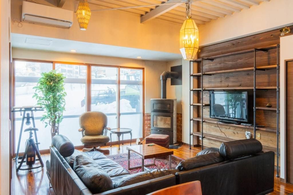 A modern living room with a fireplace, a television, and a large window overlooking a snowy landscape.
