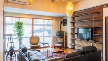 A modern living room with a fireplace, a television, and a large window overlooking a snowy landscape.