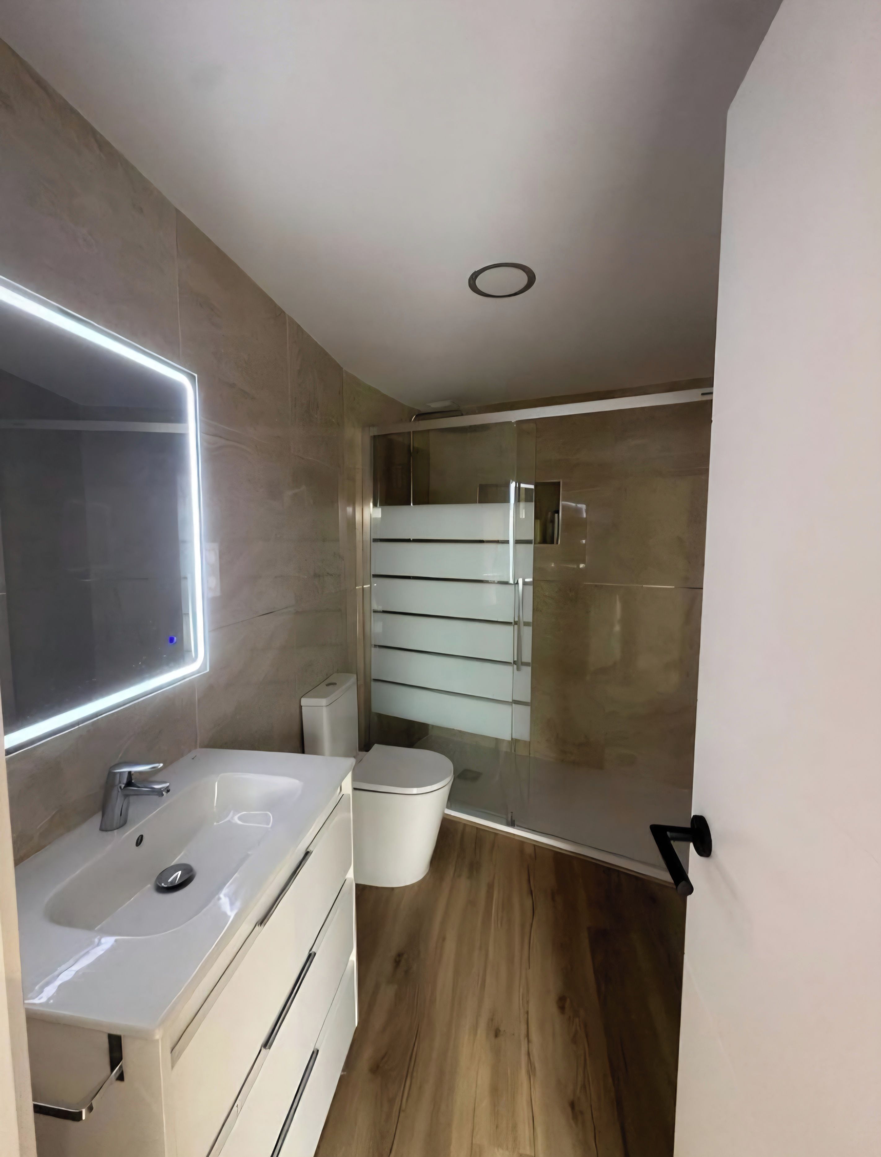 Een moderne badkamer met een grote spiegel, een wastafel en een toilet.