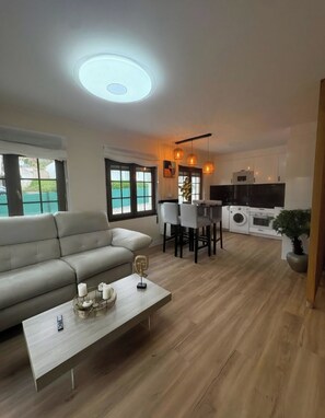 A modern living room with a sofa, coffee table, and dining area.