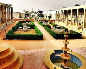 A courtyard with a fountain, neatly trimmed hedges, and outdoor seating areas. - The Mamas Resort and Camp (Jaisalmer)