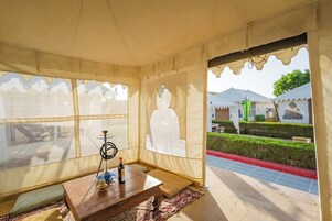 Una habitación con tienda que incluye una mesa de madera, un narguile y vistas a un jardín y edificios.