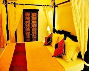 A bed with a canopy, a bedside table with a lamp, and a door with a metal grille. - The Mamas Resort and Camp (Jaisalmer)