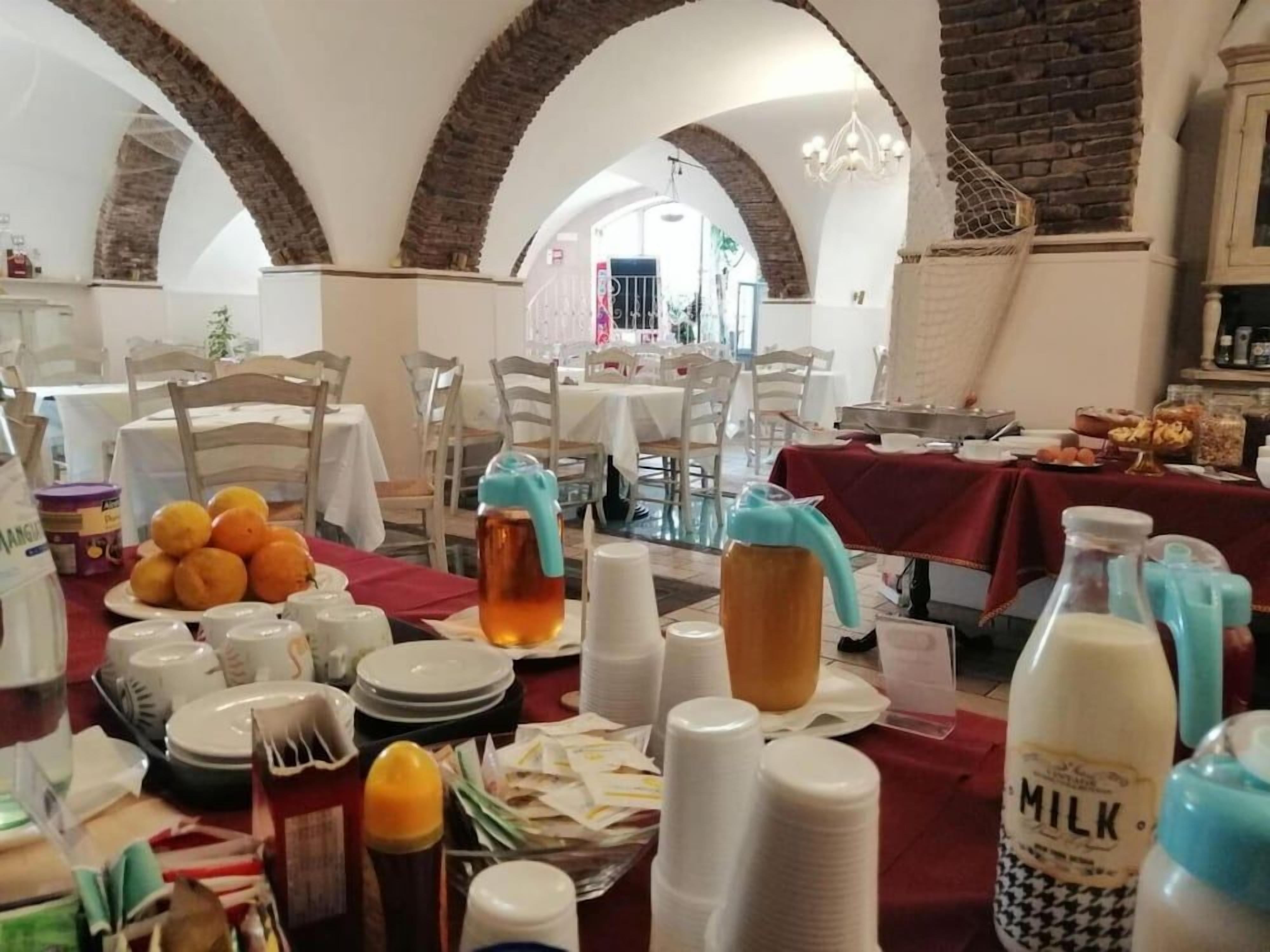 A dining area with tables set for a meal, featuring a variety of dishes, drinks, and a large milk bottle.