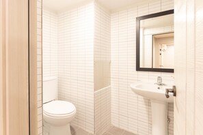 Un baño con inodoro, lavamanos y espejo.