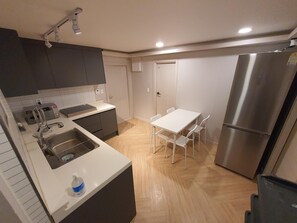 Una cocina compacta con lavamanos, microondas, refrigerador y una pequeña mesa de comedor con sillas.