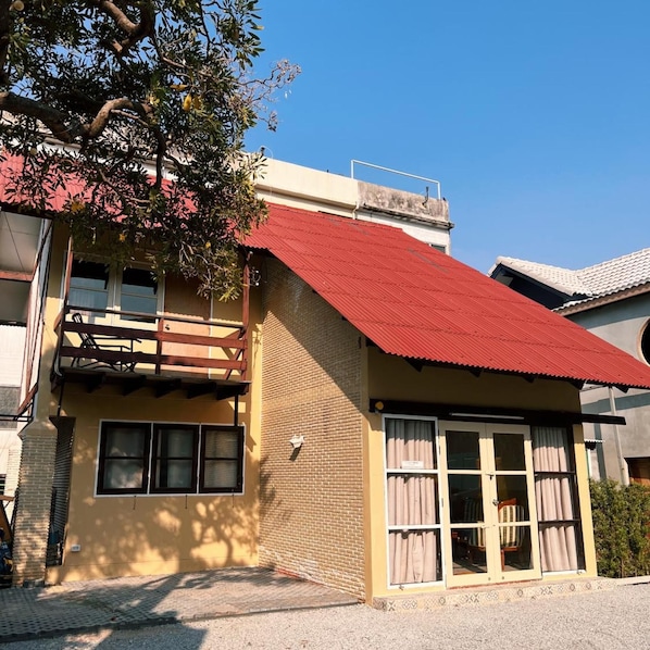 A two-story building with a red roof, a balcony, and a window with curtains. - Malarer Boutique Hostel (Chonburi)