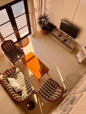 A living room with a sofa set, a coffee table, a television, and a potted plant. - Malarer Boutique Hostel (Chonburi)