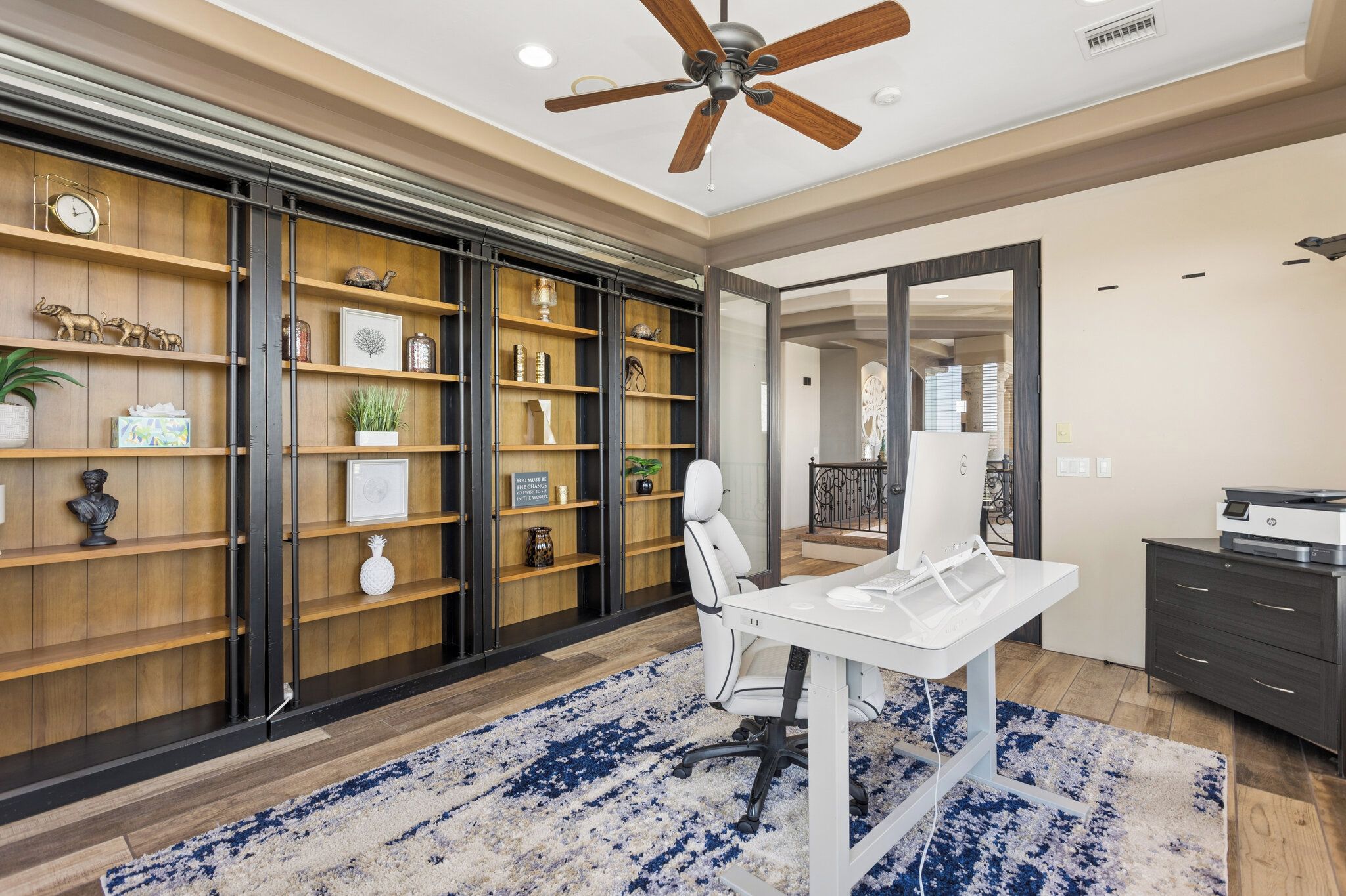 Un espace de bureau moderne comprenant un bureau, une chaise et des étagères remplies d’objets décoratifs.