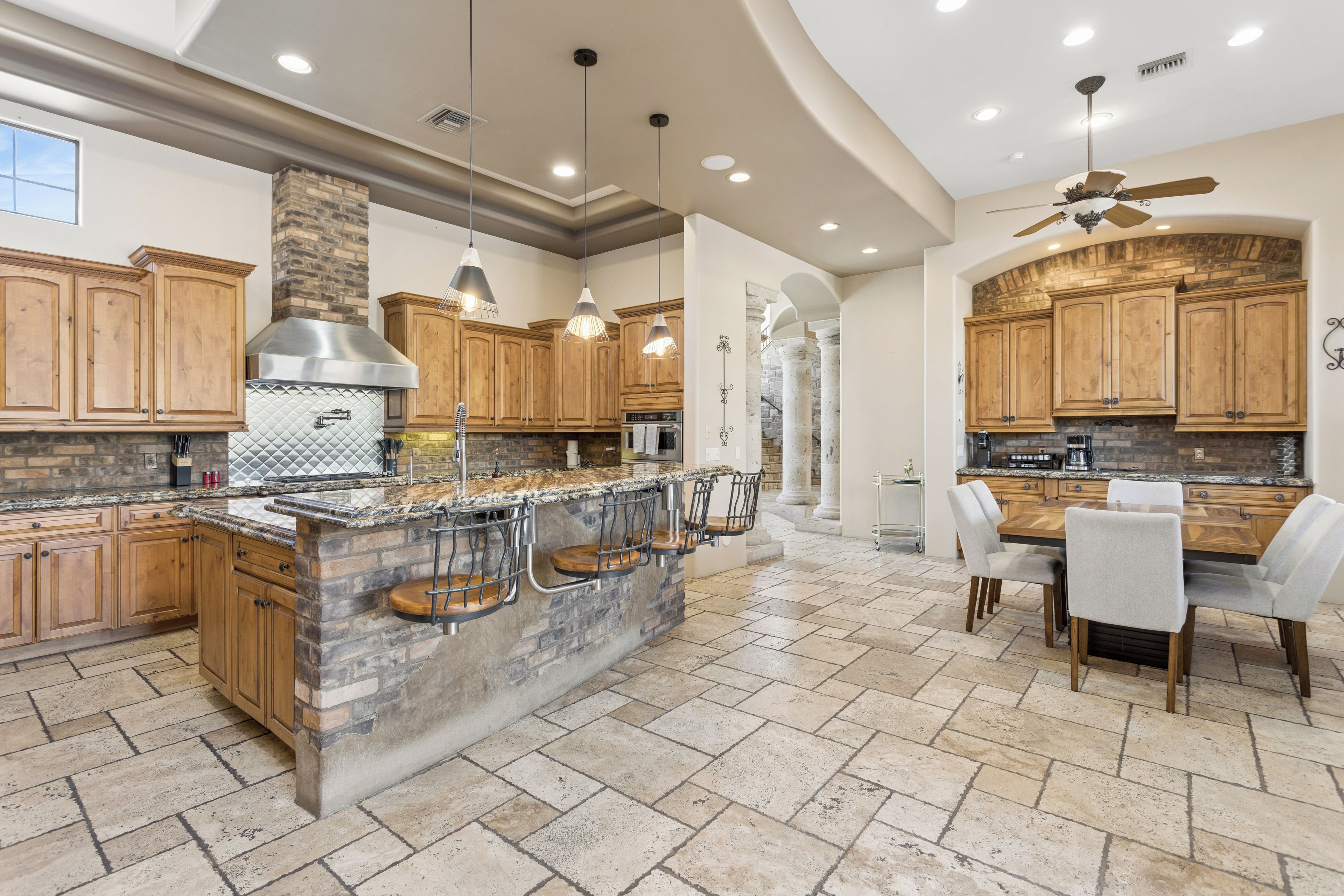 A spacious kitchen with wooden cabinets, a granite countertop, and a central island with bar stools.