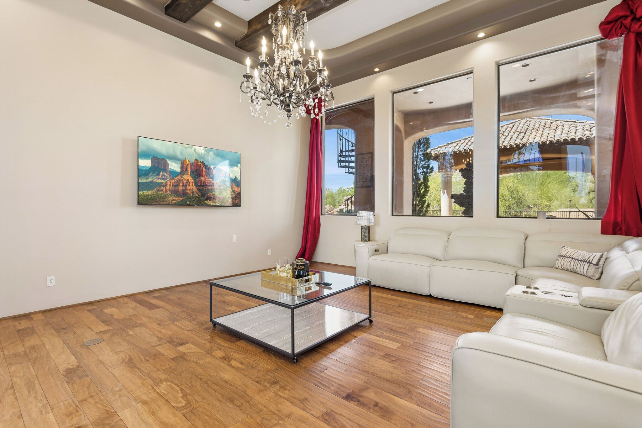 A modern living room with a glass coffee table, a white sofa, and a large painting of a landscape.