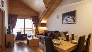 Una stanza accogliente con soffitto in legno, un tavolo da pranzo apparecchiato per due e un divano.