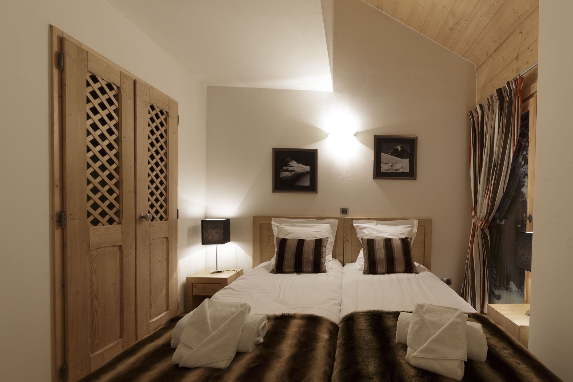Un letto matrimoniale con due cuscini, una lampada da comodino e un'armadio in legno con decorazioni a griglia.